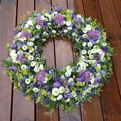 Begravelseskrans „Blomsterkrans årstidensfarver i lyseblå, medium“ fra Miss Liss Blomster