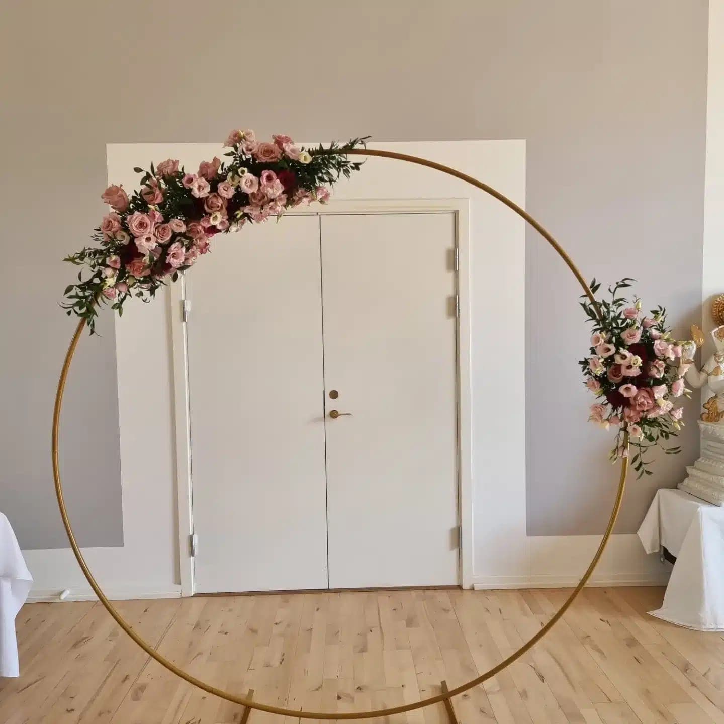 Rund blomsterbue med roser foran en hvid dør