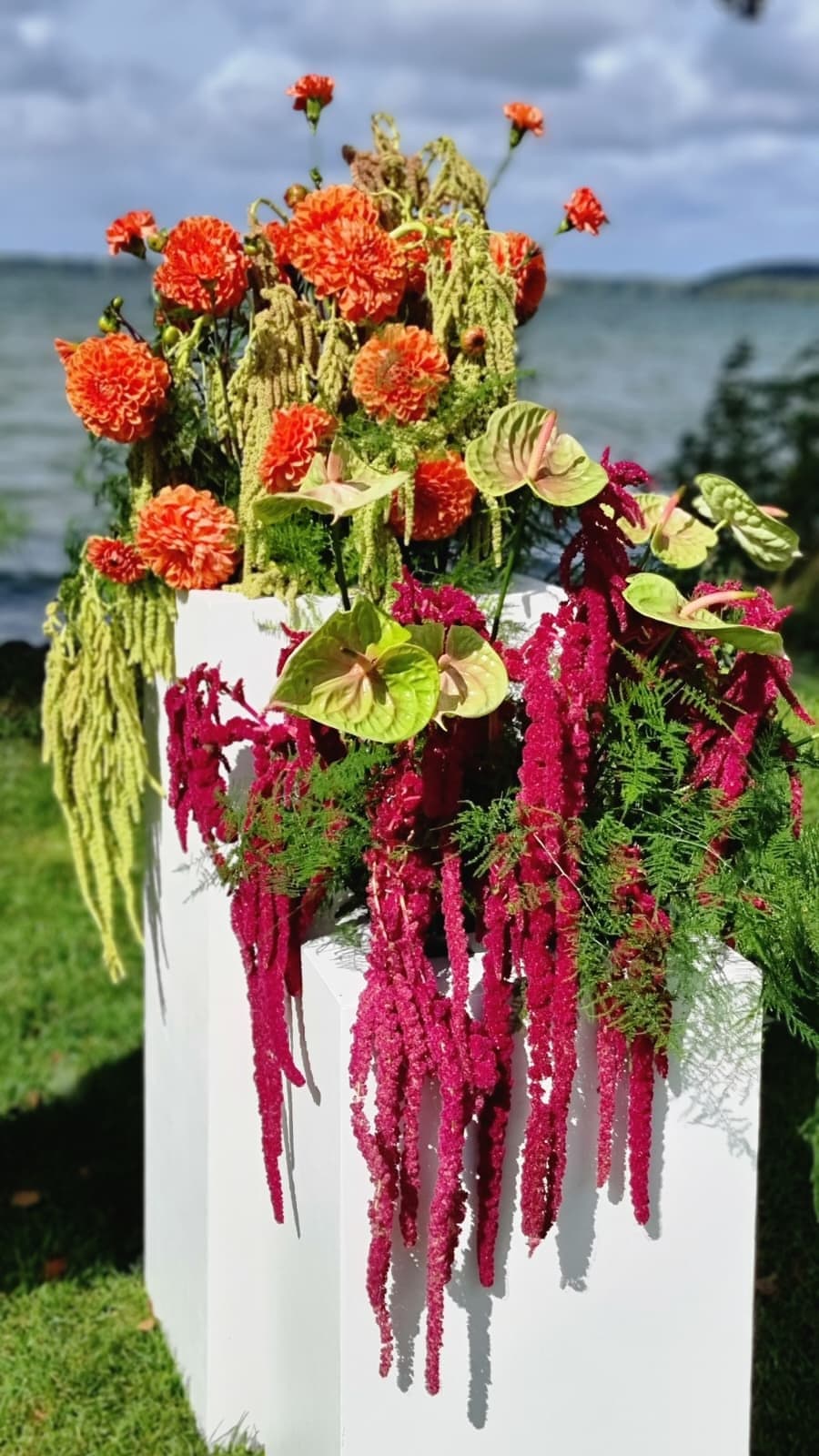 Stor dekoration med dahlia, amaranthus og anthurium på hvide podier ved vandet