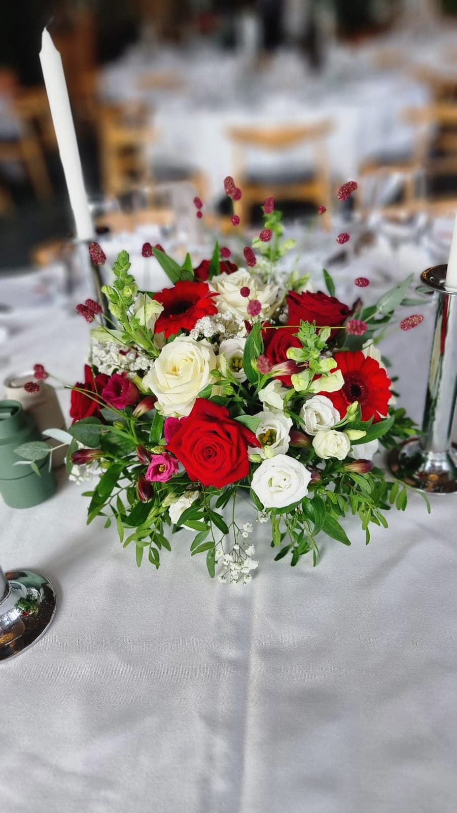 Borddekoration med røde og hvide roser, gerbera og eustoma på festbord