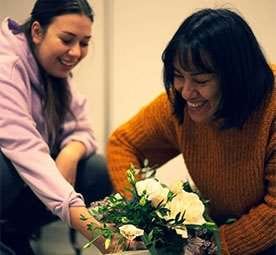 Lissette og en kollega griner, mens de arrangerer blomster